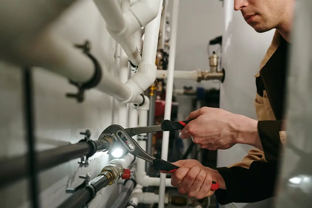 Expert plumber using a tool to fix parts of pipes during work