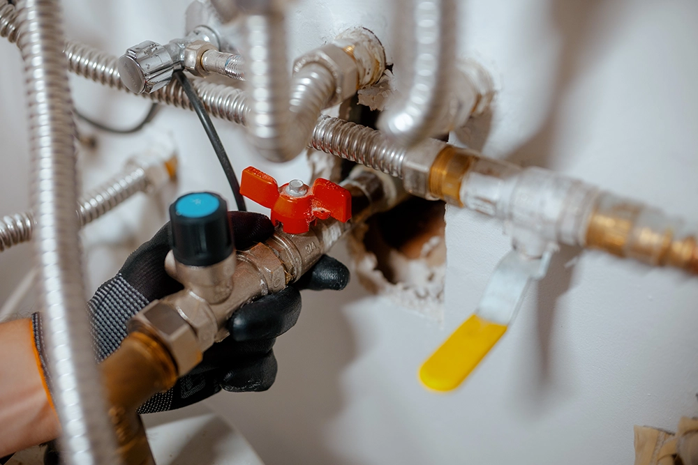 Expert plumber working on complex brass valves and flexible plumbing pipes.